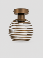 Black coiled metal flush ceiling light with an opal glass globe on a light gray studio background