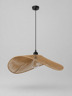 Wide brim woven rattan pendant light on a light gray studio background