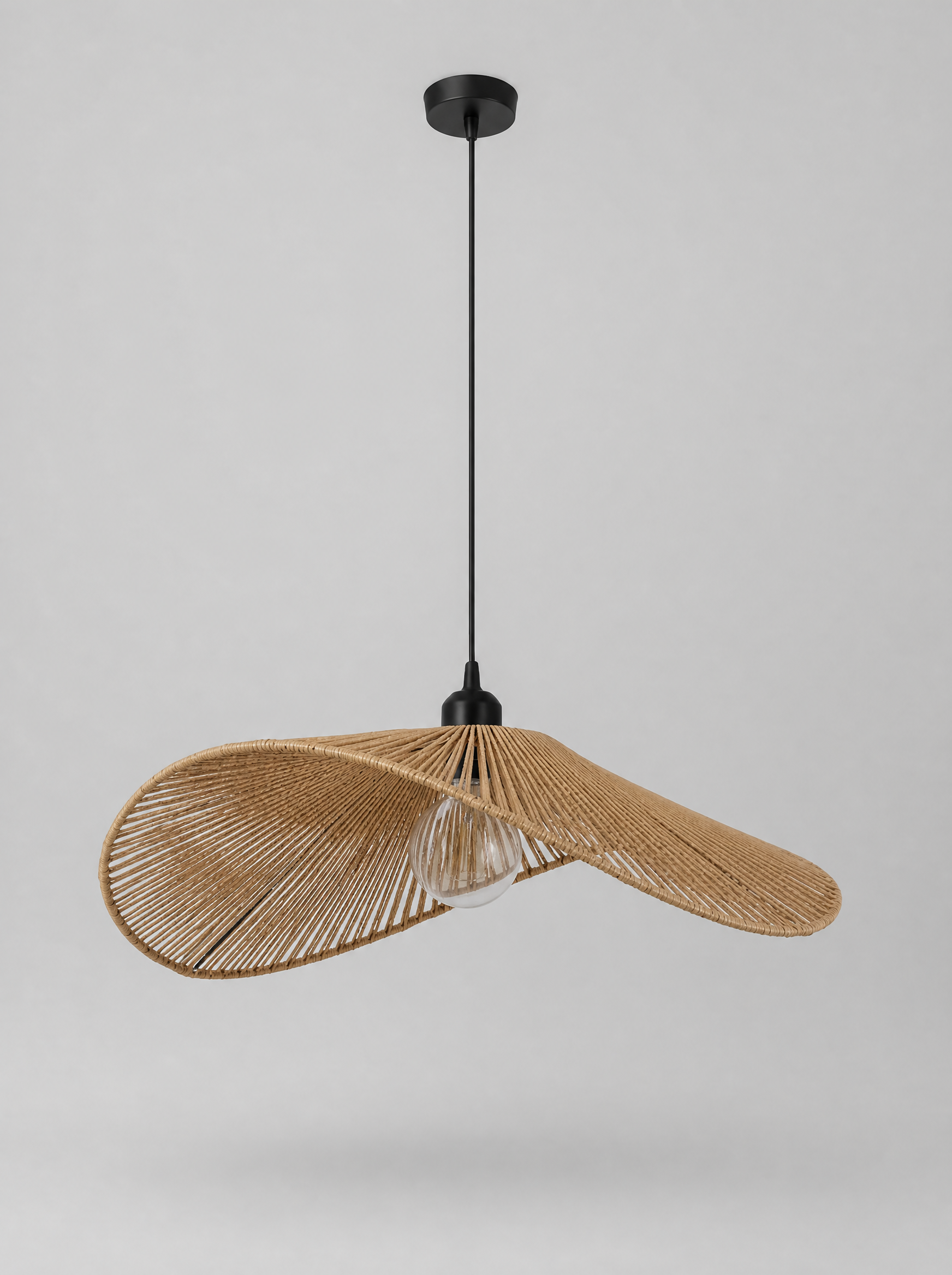 Wide brim woven rattan pendant light on a light gray studio background