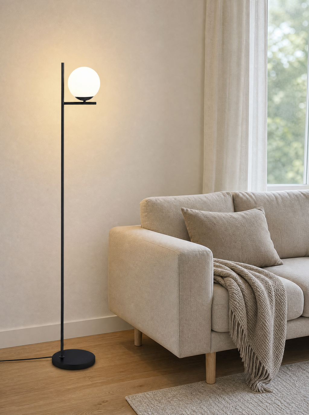Single globe floor lamp lit at the end of a sofa in a living room