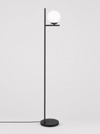 Black floor lamp with a single opal glass globe on a light gray studio background