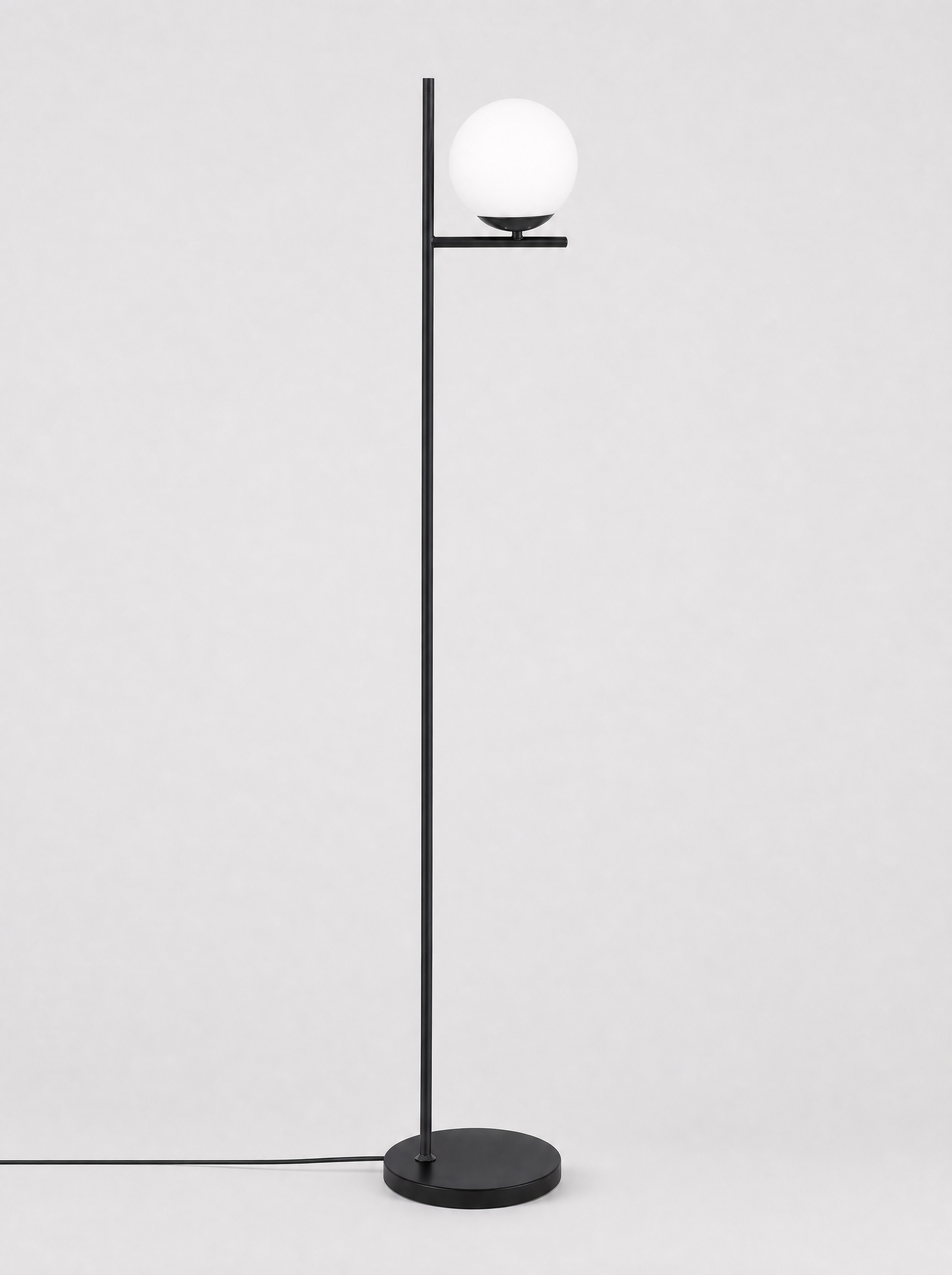 Black floor lamp with a single opal glass globe on a light gray studio background