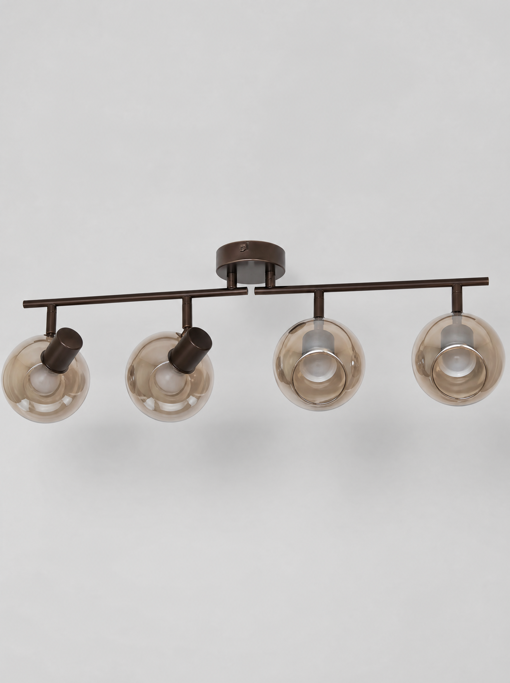Black four head ceiling spot bar with smoked glass globes on a light gray studio background