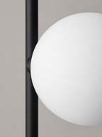 Close up of one opal glass globe where it meets the black arm