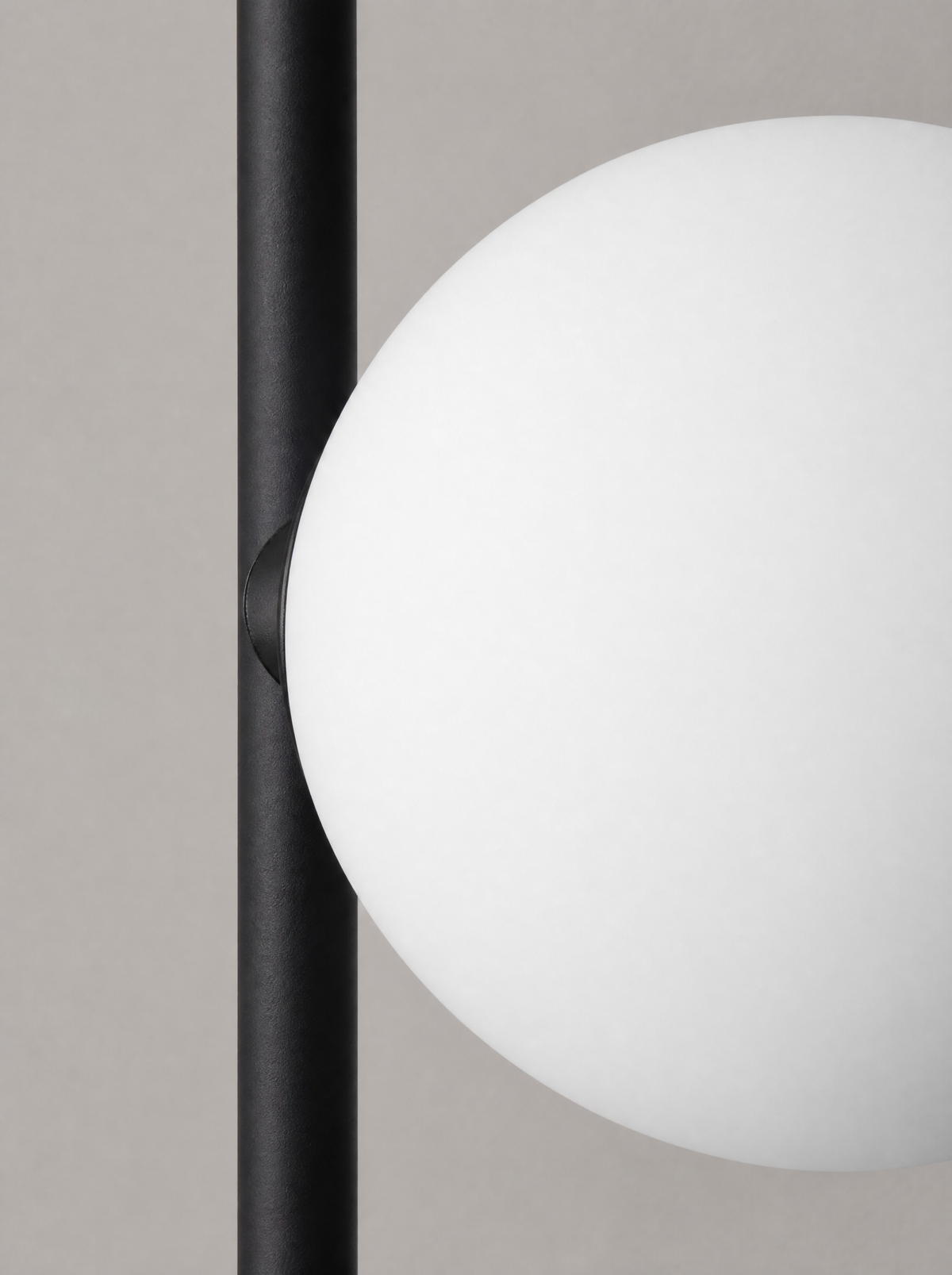 Close up of one opal glass globe where it meets the black arm