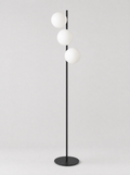 Black floor lamp with three staggered opal glass globes on a light gray studio background