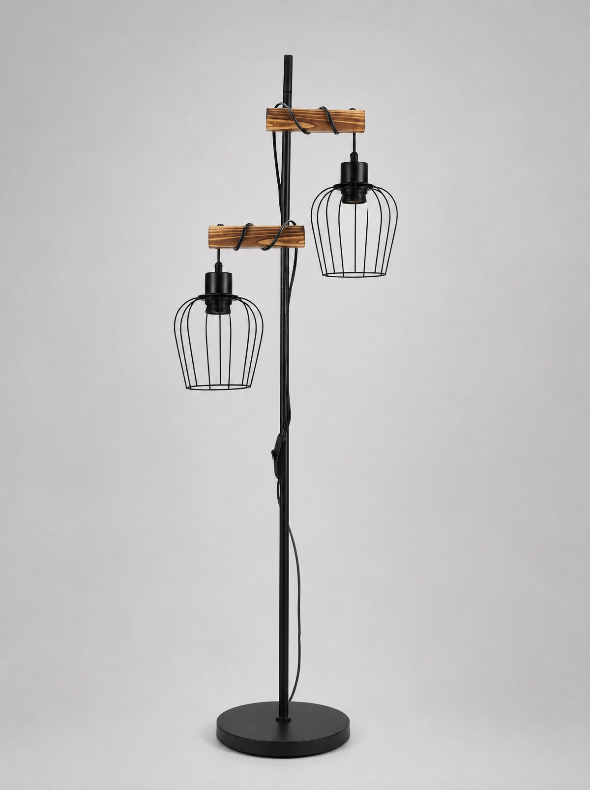 Black floor lamp with two wire cage shades on wood arms on a light gray studio background