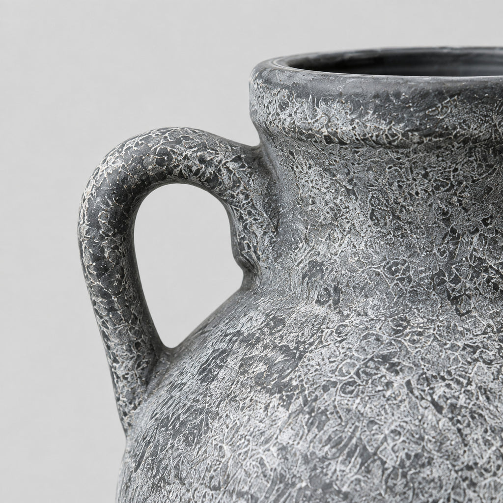 Close up of the curved side handle of the weathered gray ceramic amphora vase