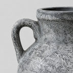 Close up of the curved side handle of the weathered gray ceramic amphora vase