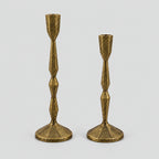 Set of two faceted cast iron taper candle holders in Antique Brass on a light gray studio background