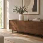 Textured White ceramic jar vase on a 160 cm wide walnut sideboard beneath a framed print with a bunch of eucalyptus in the vase.