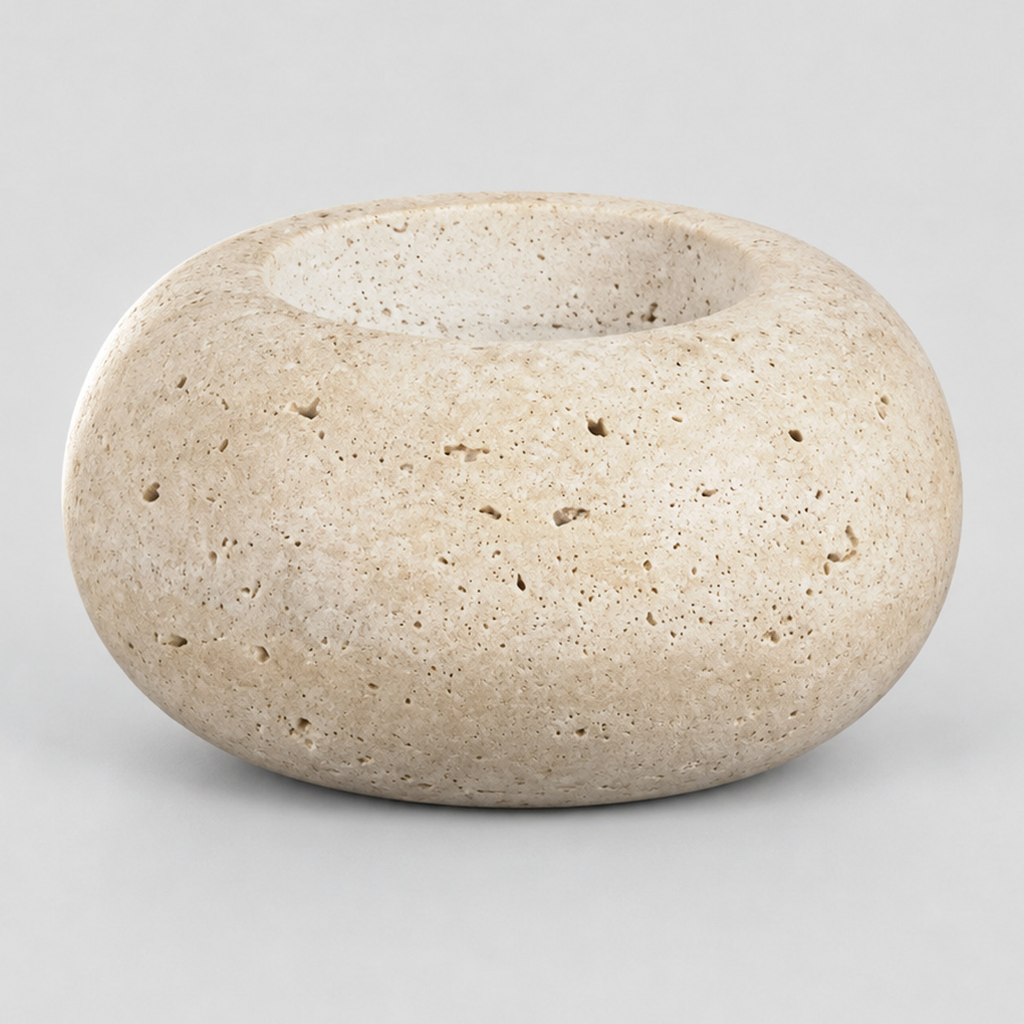 Travertine stone candle holder on a light gray studio background.