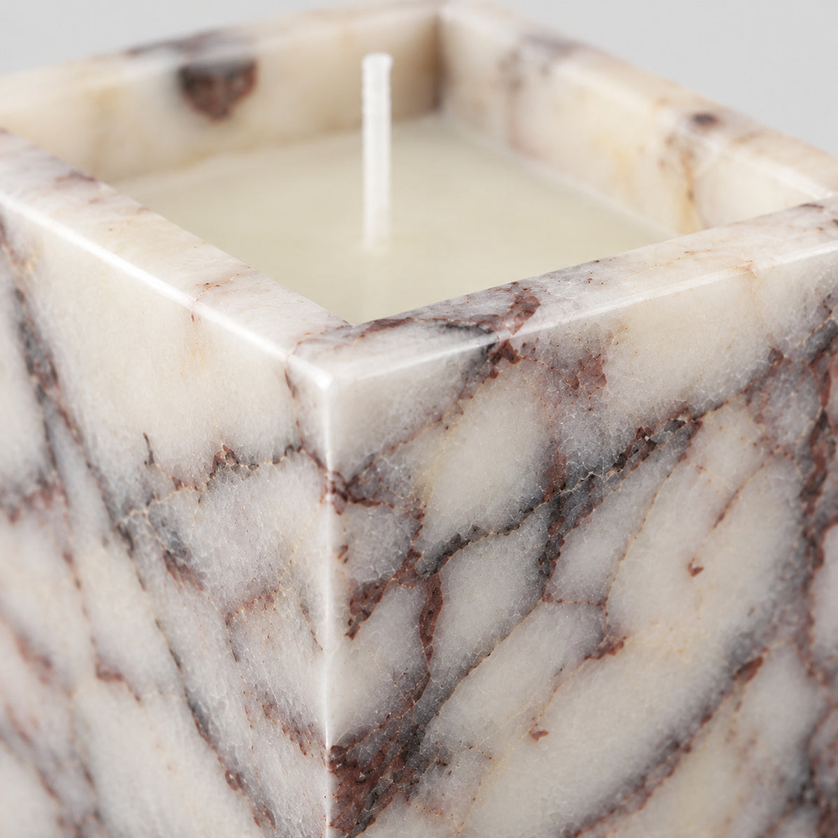 Close up of the mitered corner joint of the Calacatta Viola square marble candle holder.