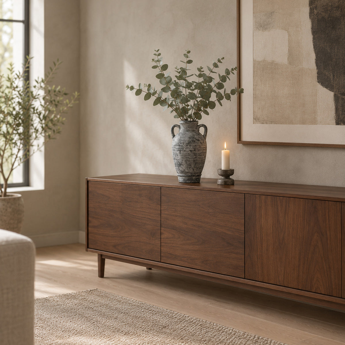 Weathered gray ceramic amphora vase on a walnut sideboard with eucalyptus in the vase
