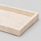Close up of the raised rectangular rim of the natural beige travertine rectangular tray.
