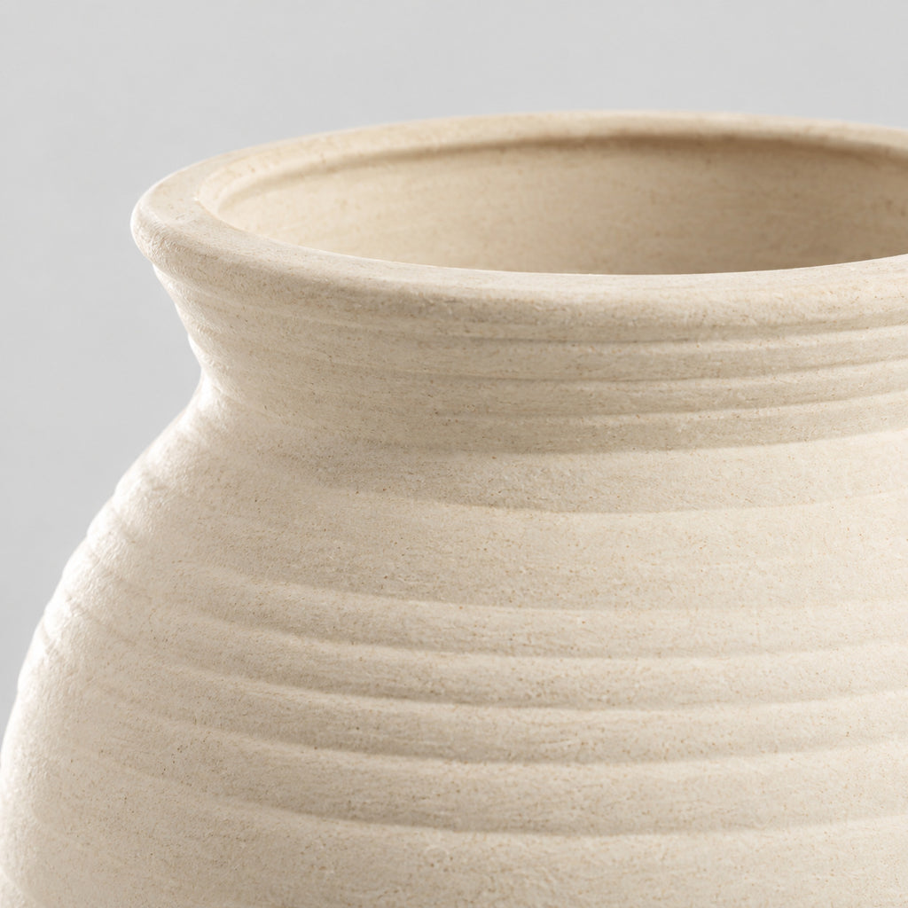 Close up of the smooth flared rim of the off-white ceramic vase.