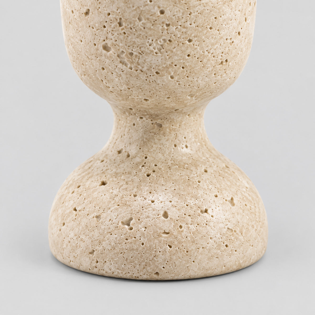 Close up of the rounded pedestal base of the travertine candle holder.