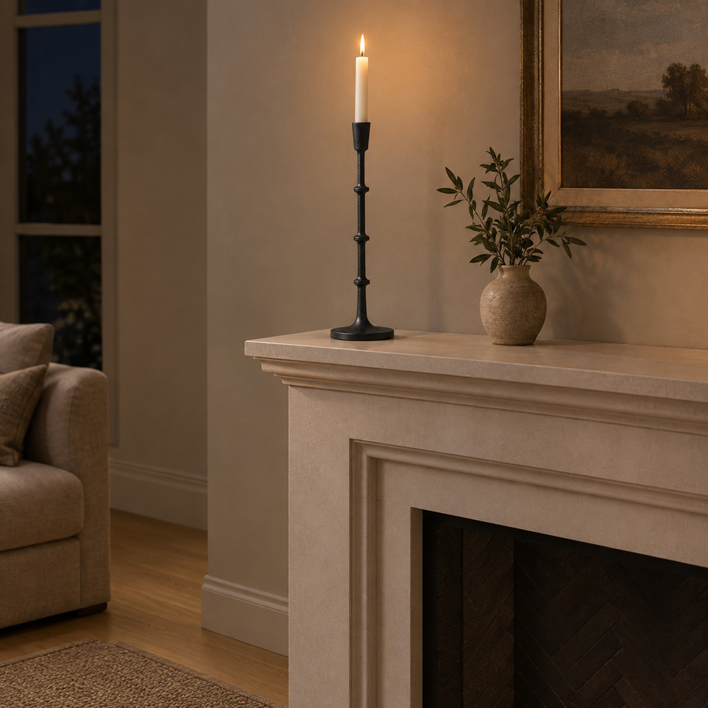 Matte Black cast-iron taper candle holder on a mantelpiece above a fireplace with one lit taper candle