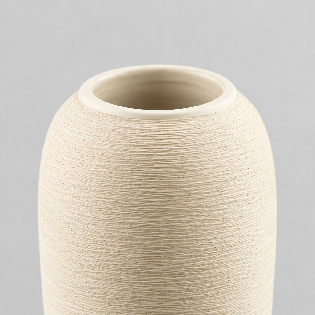 Close up of the smooth rounded rim at the mouth of the off-white tall ribbed stoneware vase.