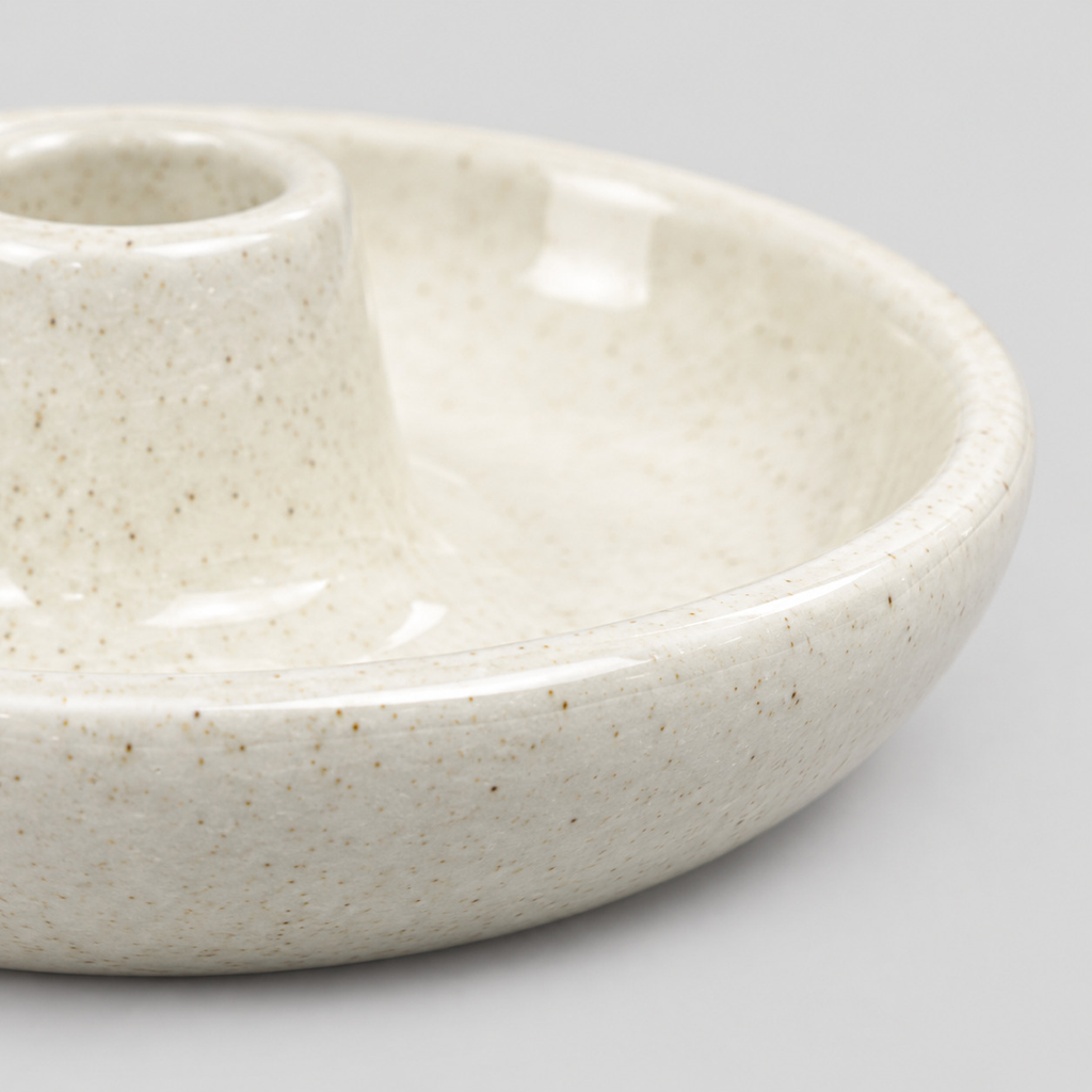 Close up of the smooth rounded rim of the dish of the ceramic taper candle holder in Speckled Off-White