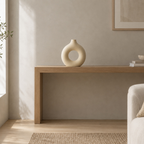 Beige hollow round ceramic vase on an oak console table in a calm room.