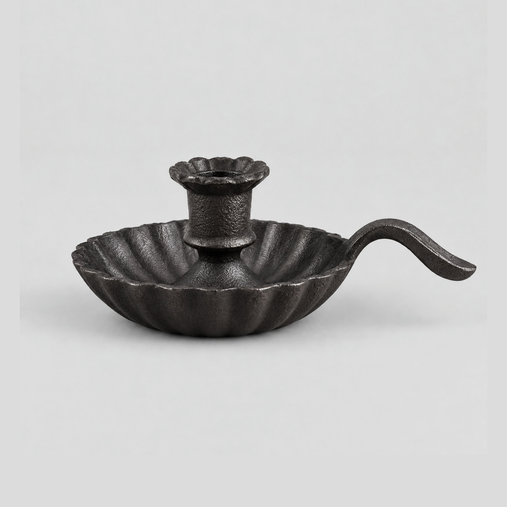Cast iron chamberstick candle holder in Cast Iron finish on a light gray studio background