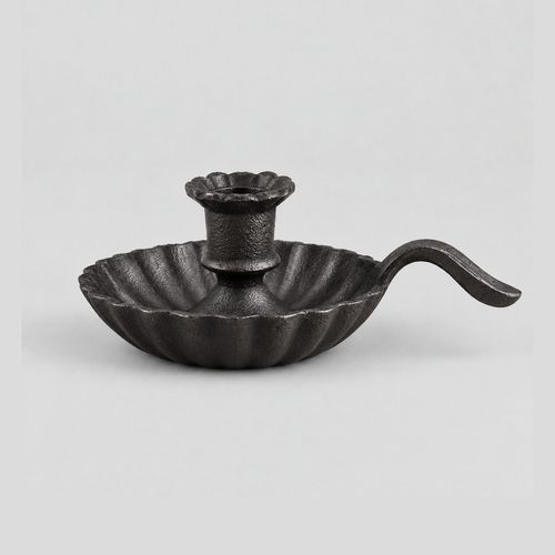 Cast iron chamberstick candle holder in Cast Iron finish on a light gray studio background