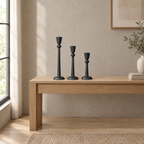 Matte black cast-iron taper candle holder set on an oak console table in a calm room.