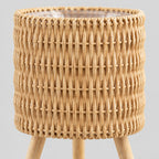 Close up of the vertical weave of the rattan basket on the standing woven rattan planter basket on wooden tripod legs in Natural Rattan.