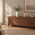 Off-white ribbed ceramic vase on a walnut sideboard styled with eucalyptus stems.