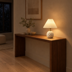 Fluted ceramic table lamp in Milk White lit in the evening standing on a 120 cm wide walnut console table in a hallway, the only light in the room