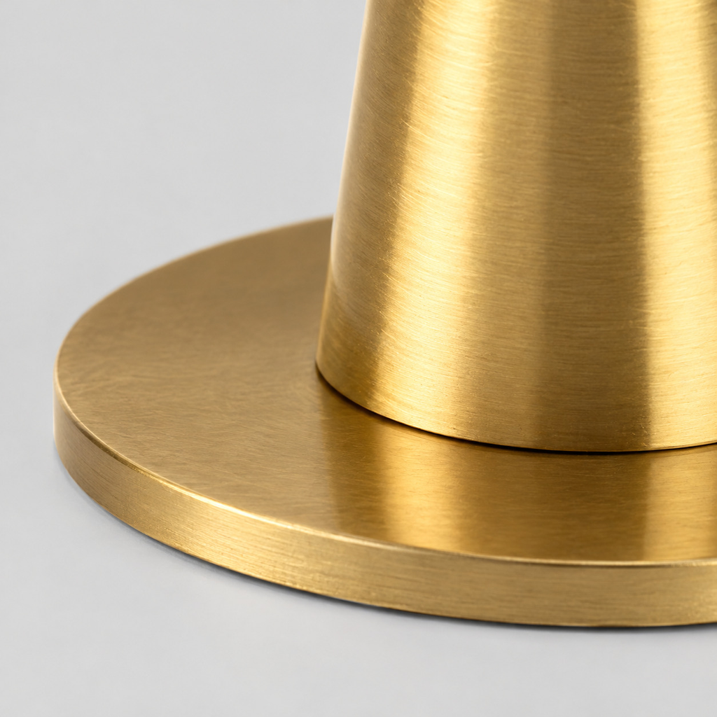 Close up of the flat circular base of the brushed brass taper candle holder.